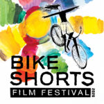 colourful illustration with "BIKE SHORTS FILM FESTIVAL" in large black letters over a wash of several different colours. An ink-pen style illustration of a person on a bike with arms outstretched is beside the text.